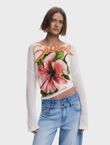 A model showcases a white sweater adorned with a colorful floral design.