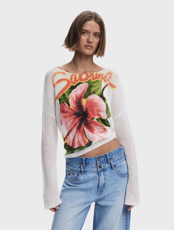 A model showcases a white sweater adorned with a colorful floral design.