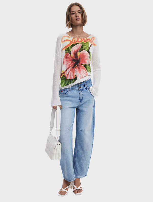The model is dressed in a white sweater featuring a vibrant floral pattern.