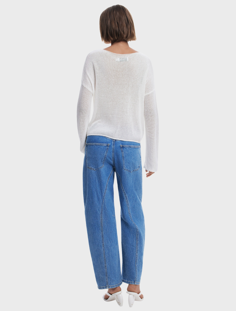 The model displays a white sweater with an intricate floral design.