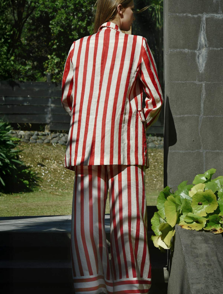 A woman showcases a fashionable red and white striped suit, presenting a bold and contemporary look.