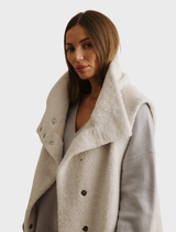 Latte Sherpa cuddle gilet, offering a plush texture and sleeveless design, perfect for added warmth and comfort.