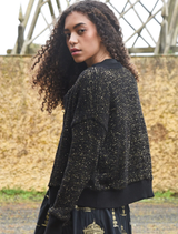 Elegant black and gold cardigan, Shine Of The Times, showcasing a luxurious texture and modern silhouette.