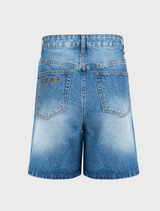 denim shorts stands confidently, showcasing a casual summer outfit.