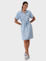 A woman wearing a denim shirt dress with a shirt collar, made from lyocell fabric, standing confidently.