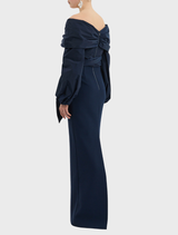 Navy dress, the Sibylla Gown, adorned with a decorative bow on the shoulder.