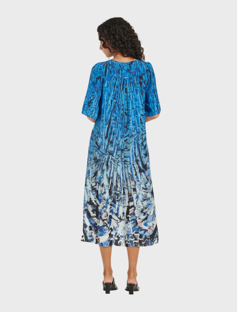 A woman is dressed in a blue and white floral print dress, featuring a lively floral pattern that enhances her appearance.