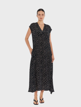 The black polka dot dress, called Maxi Slice Dress - Black/Meringue, is worn by a woman in the image.