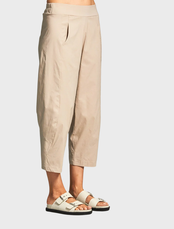 A woman stands wearing sandals and cropped pants, showcasing a casual summer outfit.