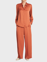 A copper-colored soft shirt hanging, illustrating its lightweight material and casual aesthetic.