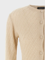 Beige knit cardigan draped over a chair, highlighting its cozy fabric and versatile design for everyday wear.