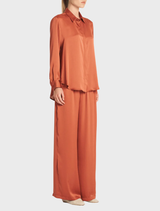 A copper shirt made of soft fabric, elegantly draped on a hanger, emphasizing its relaxed style.