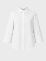 Soft white oversized shirt with broderie anglaise, long wide sleeves with slits, a collar, and button closure at the front.