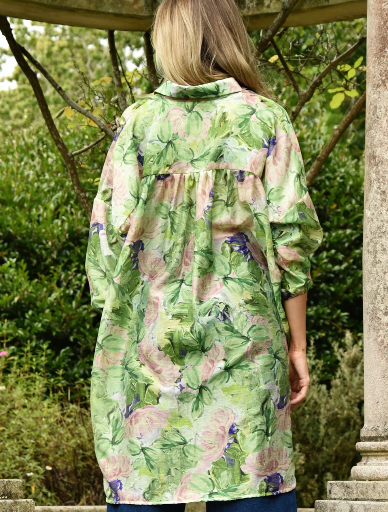 Back view of a woman in a green floral print coat, showcasing the design of the Something Borrowed shirt.