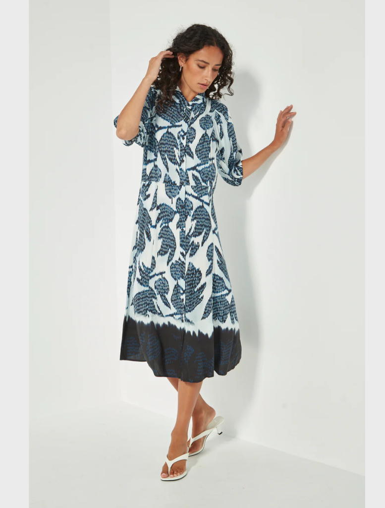 A model showcases a blue and white floral print dress, highlighting its vibrant colors and elegant design.