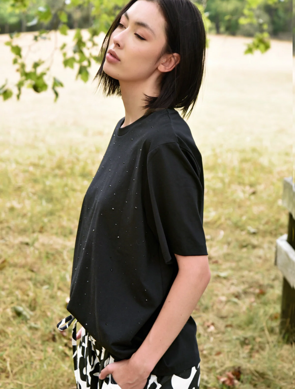 A woman dressed in black and white pants and a black t-shirt featuring Sparkle Magic.