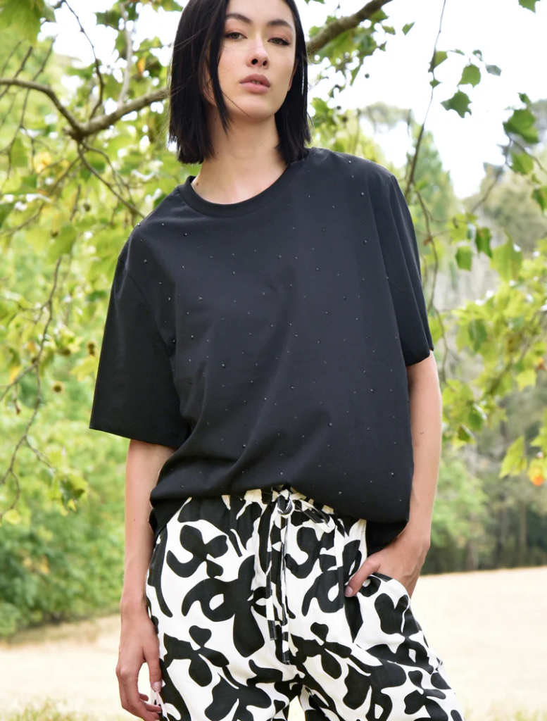 A woman wearing black and white pants with a black "Sparkle Magic" t-shirt.