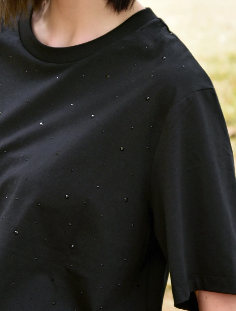 A woman in a black t-shirt adorned with silver dots, showcasing the Sparkle Magic design.