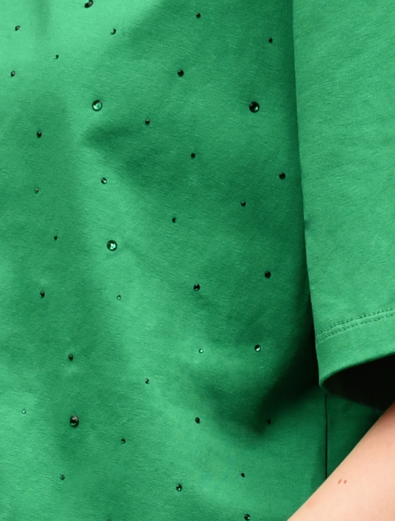 Detailed view of a green shirt with black dots, labeled as Sparkle Magic T-shirt.