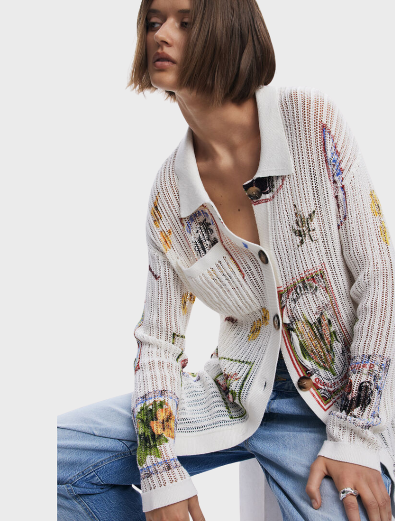 A model wears a white shirt embellished with a lively floral pattern.