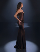 Strapless bronze gown with asymmetrical neckline, flowing skirt, refined pleating, and high leg split for a sophisticated look.
