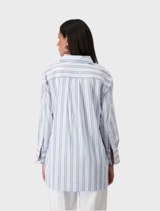 Back view of a woman in a blue and white striped shirt with a collar, set against a light sky background.