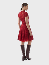 A ruby red A-line dress named Carmen, characterized by its fitted bodice and flared skirt, elegantly showcased on a stand.