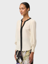 Chic silk blouse in cloud shade, adorned with pleated cuffs for a refined and elegant appearance.