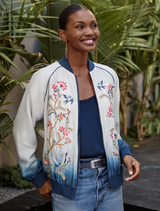Teresa Bomber Jacket featuring a white to blue ombre, floral embroidery, and contrasting ribbing, designed for two-way wear.