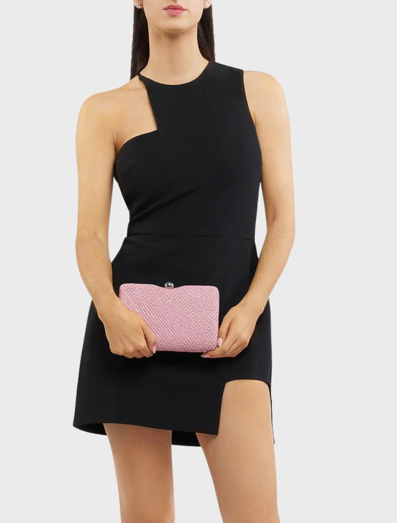 A woman in a black dress is seen holding a pink Birdie Textural Handle Bag, blending fashion with vibrant accessories.