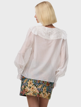 The Thea Blouse in Antique offers vintage charm with its floral lace bib and ruffle trim, crafted from a luxurious silk cotton blend.