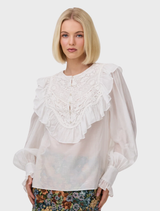 The Thea Blouse in Antique showcases a floral lace bib and ruffle trim, crafted from luxurious silk cotton for a feminine style.
