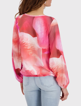 Monari blouse showcasing a vibrant pink floral design, round neck, long sleeves, and elasticized sleeve and hem for comfort.