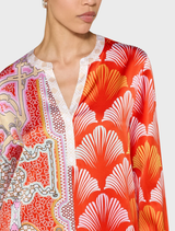 A woman dressed in a colorful tomato multi blouse and matching pants, exuding a lively fashion sense.