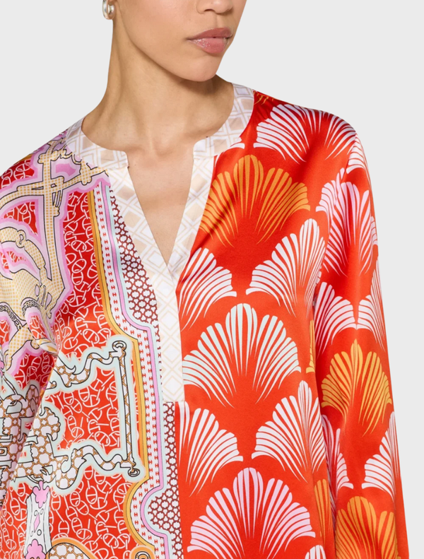 A woman dressed in a colorful tomato multi blouse and matching pants, exuding a lively fashion sense.