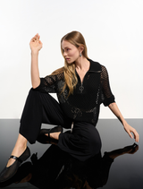 Black top displayed on a hanger, showcasing its simple and elegant design.