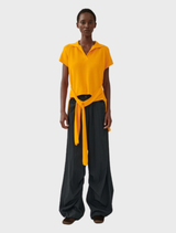 A stylish orange top displayed on a hanger, showcasing its simple design and fabric texture.