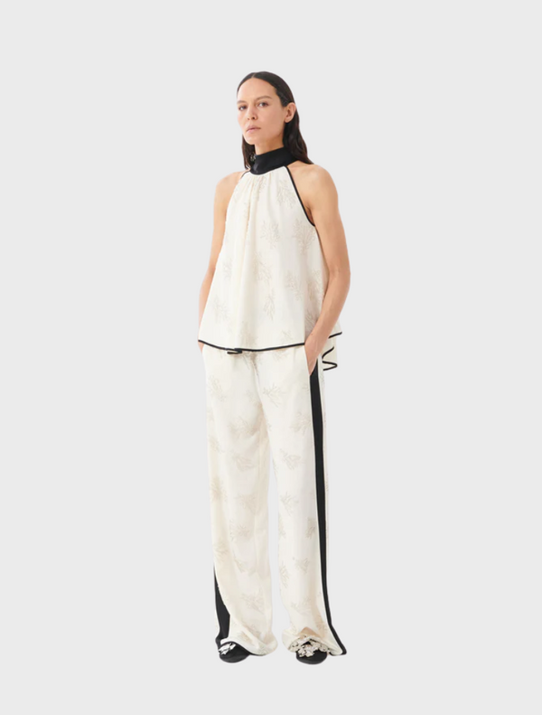 A model is dressed in a white top paired with black pants, showcasing a simple yet stylish outfit.