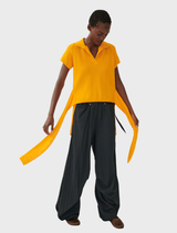 An orange top hanging against a neutral background, highlighting its clean lines and elegant appearance.
