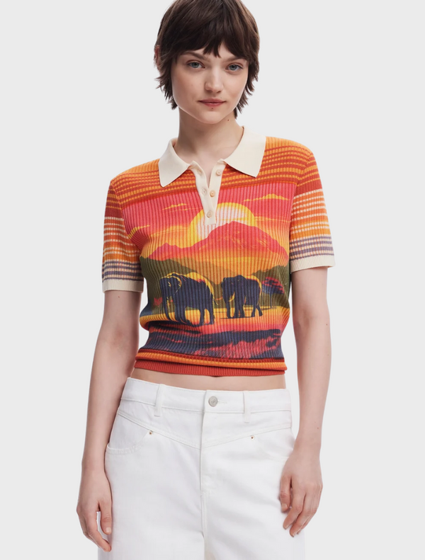 A woman in a polo shirt featuring a playful elephant print, smiling and standing outdoors.