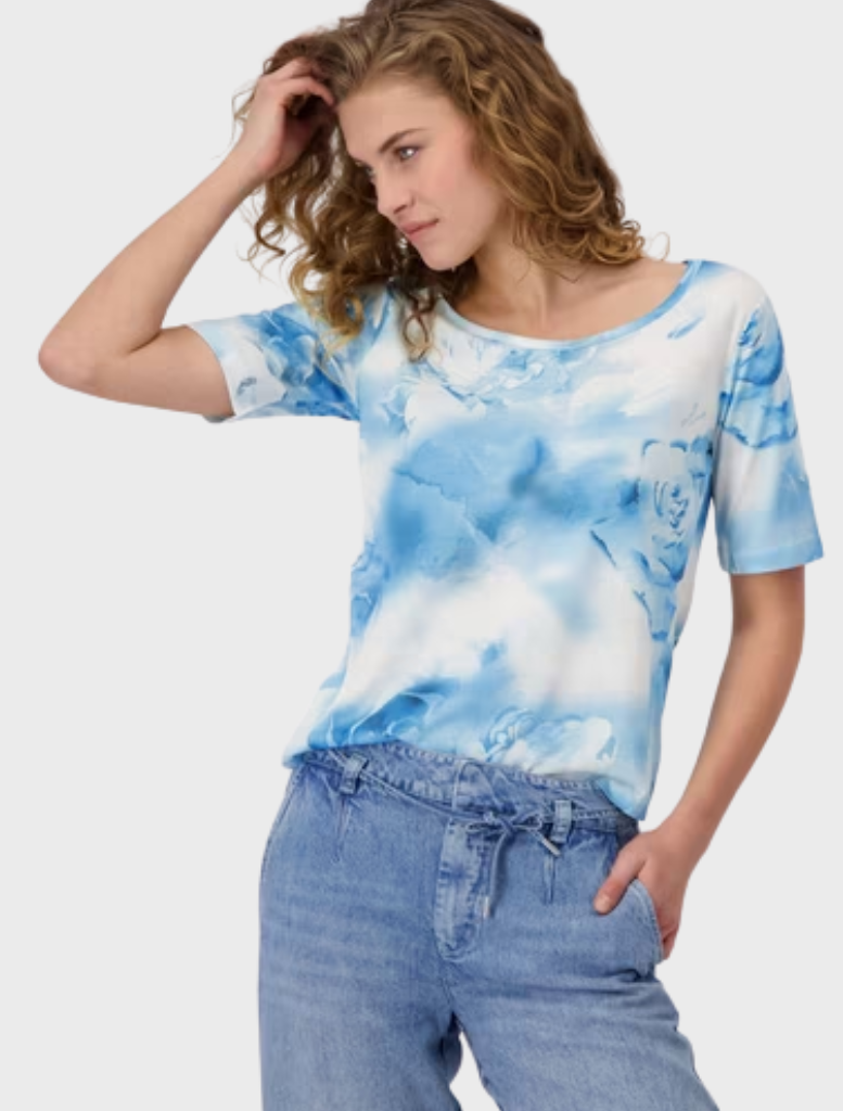 A model showcases a blue and white tie-dye shirt, featuring a vibrant swirl pattern.