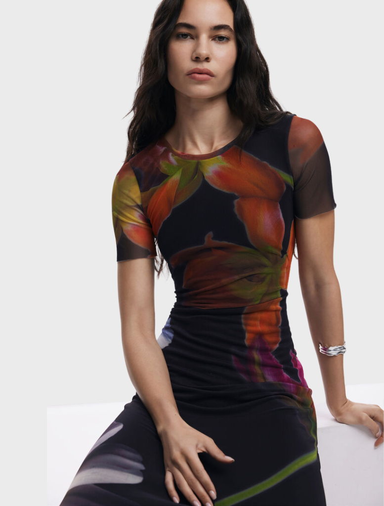 A black dress with an elegant floral print, highlighting a mix of bright flowers against a dark background.