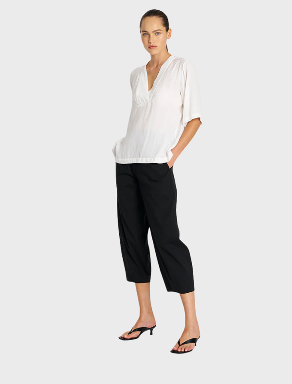A pair of black cropped Tuscan pants, highlighting their tailored fit and stylish appearance against a neutral backdrop.