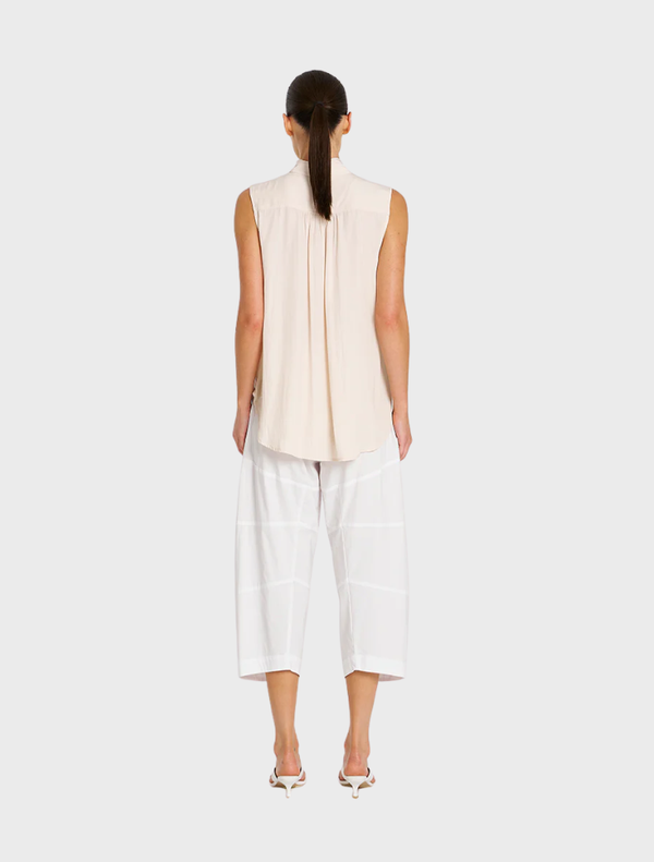 A pair of white cropped Tuscan pants laid flat, highlighting their tailored fit and stylish appearance for versatile outfits.