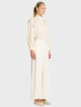 Close-up of vanilla and black suit pants, featuring a smooth fabric texture and refined tailoring details.