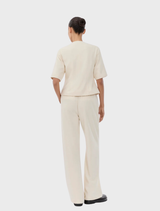 Short-sleeved tailored white blazer with a round neckline and front button closure, styled as a top or outerwear.