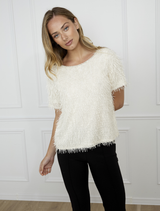 Vanilla knit top displayed on a hanger, featuring a soft texture and casual design suitable for everyday wear.