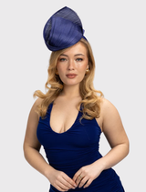 Cobalt blue fascinator with a sculptural design, featuring a ribbon-like trim on a minimalist headband for racewear styling.