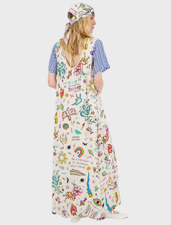 A woman models a dress adorned with bright, intricate patterns, highlighting her fashion sense and individuality.