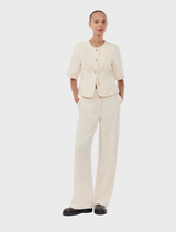 Short-sleeved white blazer with a round neckline and front button closure, styled elegantly for versatile wear.